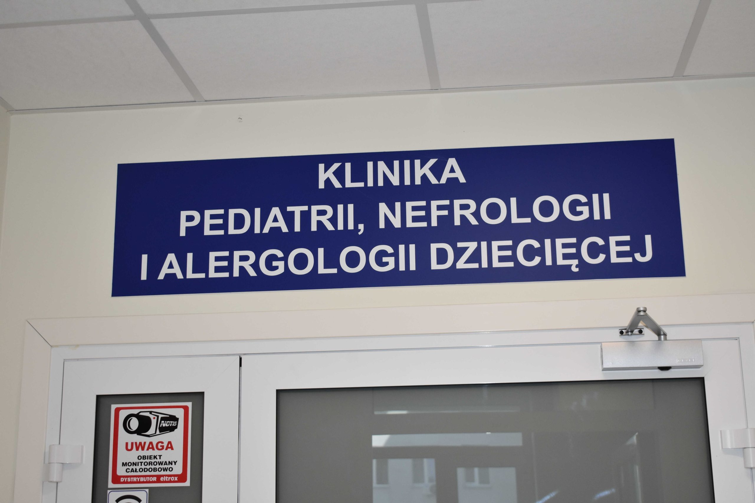 Wejście i tablica informacyjna nad drzwiami do Kliniki Pediatrii Nefrologii i Alergologi Dziecięcej