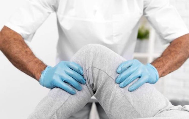 Ręce fizjoterapeuty podczas zabiegu fizjoterapii na nodze pacjenta