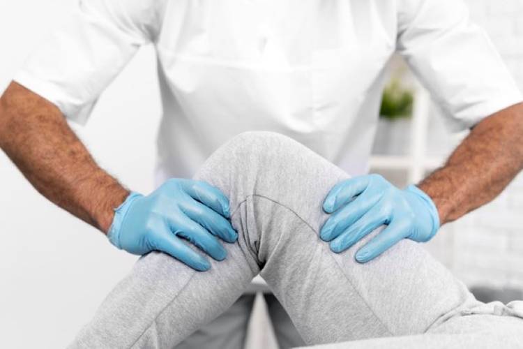 Ręce fizjoterapeuty podczas zabiegu fizjoterapii na nodze pacjenta