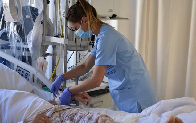 Pielęgniarka podczas pracy przy łóżku z pacjentem w szpitalu,