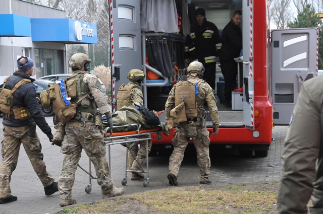 Żołnierze podczas ćwiczeń medycznych wnoszą do ambulansu poszkodowanego ułożonego na noszach.