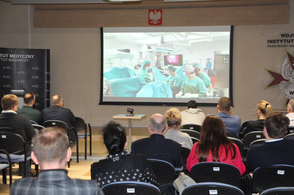 Robotic Workshop – Mastering in Deep Endometriosis w Wojskowym Instytucie Medycznym w Warszawie, Sala konferencyjna uczestnicy oglądają transmisję operacji z rzutnika.