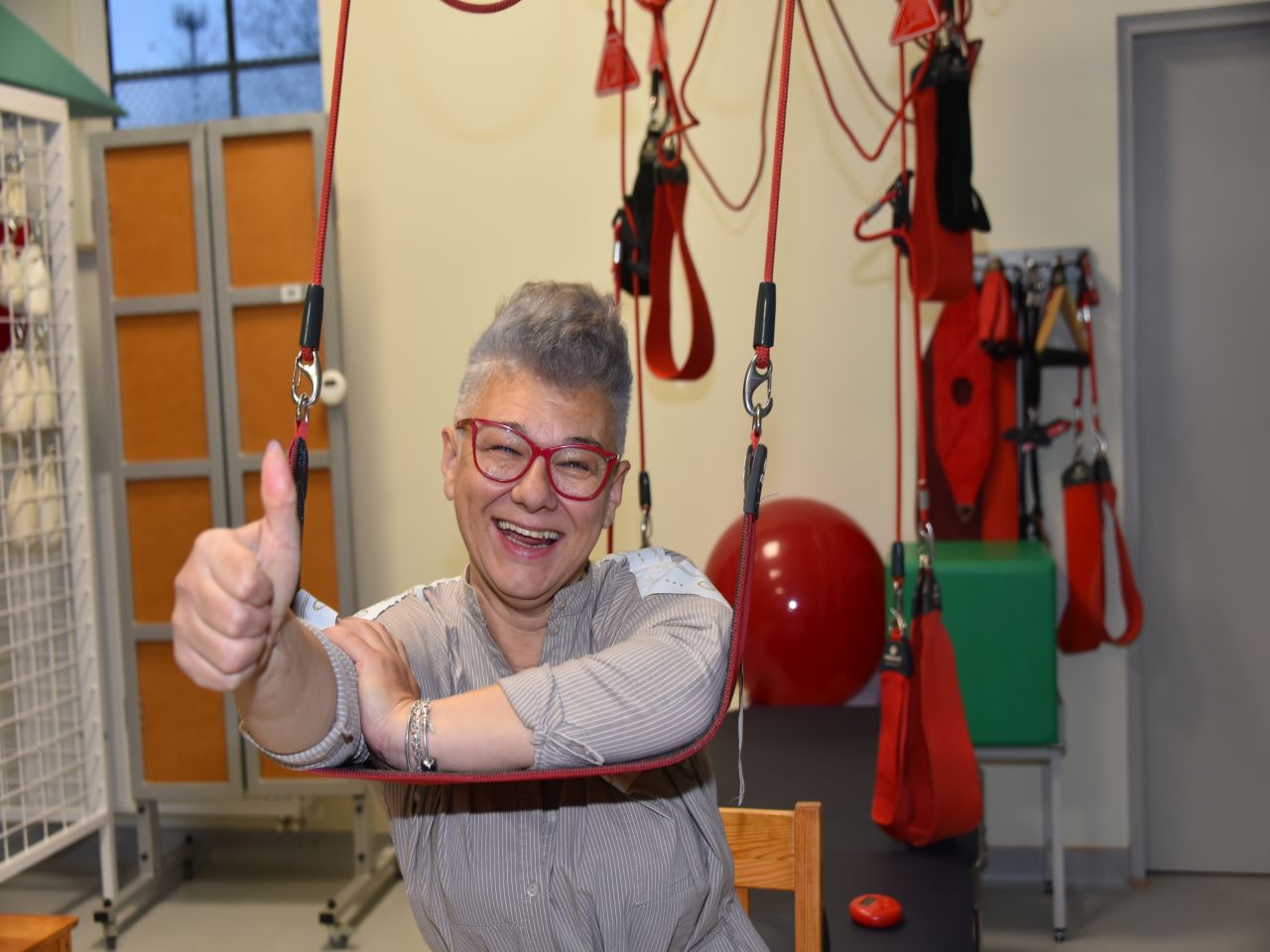 Otwarcie Budynku Rehabilitacji w WIM-PIB w Legionowie. Uśmiechnięta pacjentka podczas zabiegu rehabilitacyjnego pokazuje kciuk w górę.