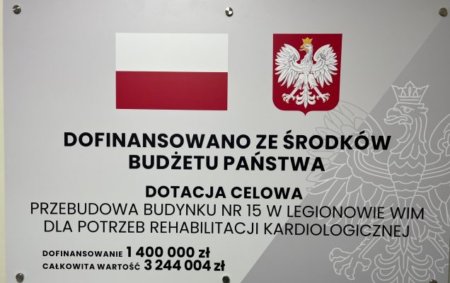Tablica informacyjna dotacji celowej. Treść tablicy: Dofinansowano ze środków budżetu państwa, dotacja celowa. Przebudowa Budynku nr 15 w Legionowie WIM dla potrzeb rehabilitacji kardiologicznej. Dofinansowanie 1400 000 zł, całkowita wartość 3244 004 zł