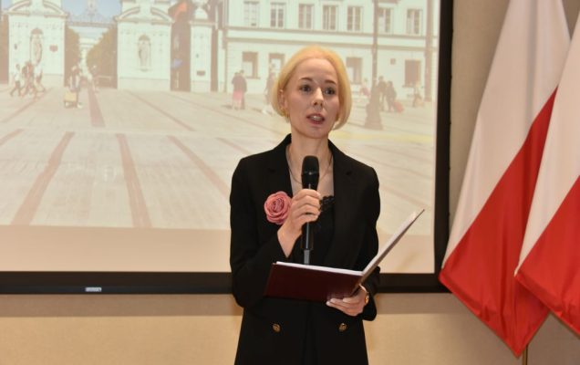 Uroczyste otwarcie Pracowni Anatomii w Wojskowym Instytucie Medycznym. Prowadząca trzyma mikrofon, za nią slajd prezentacji.