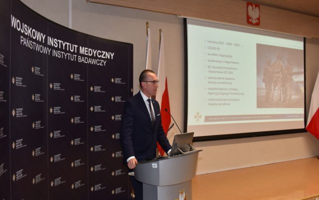 Uroczyste otwarcie Pracowni Anatomii w Wojskowym Instytucie Medycznym. Prelegent przy mównicy, za nim slajd prezentacji.