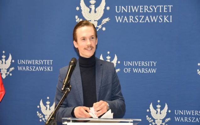 Uroczyste otwarcie Pracowni Anatomii w Wojskowym Instytucie Medycznym. Prelegent przy mównicy, za nim logo Uniwersytetu Warszawskiego.