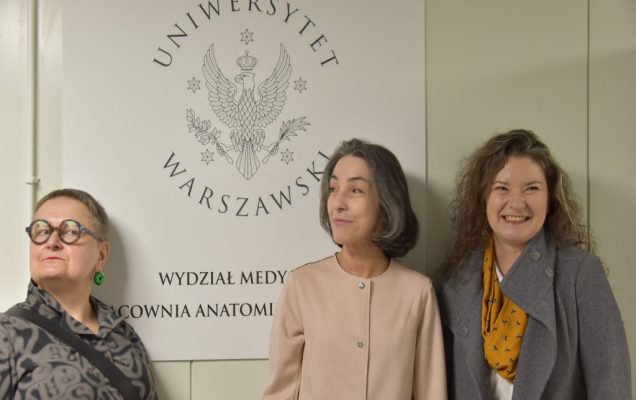 Uroczyste otwarcie Pracowni Anatomii w Wojskowym Instytucie Medycznym. Zdjęcie gości, w tle logo Uniwersytetu Warszawskiego.