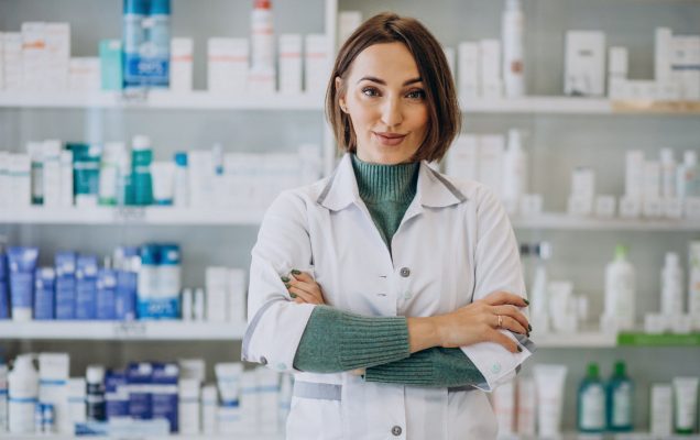 Farmaceutka w aptece z a nią półki z lekami