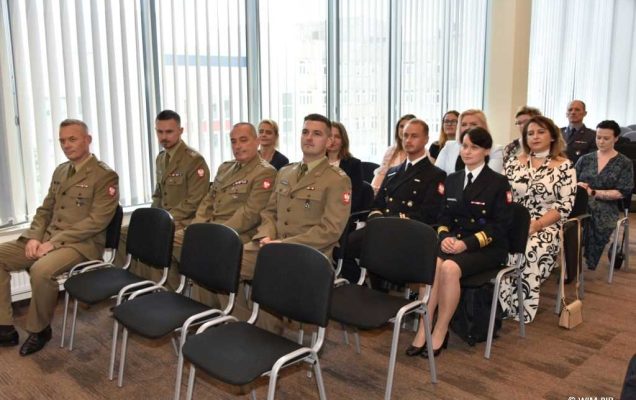 Uhonorowanie 30 absolwentów VIII edycji studiów podyplomowych w WIM-PIB, absolwenci siedzący na sali podczas uroczystości zakończenia studiów