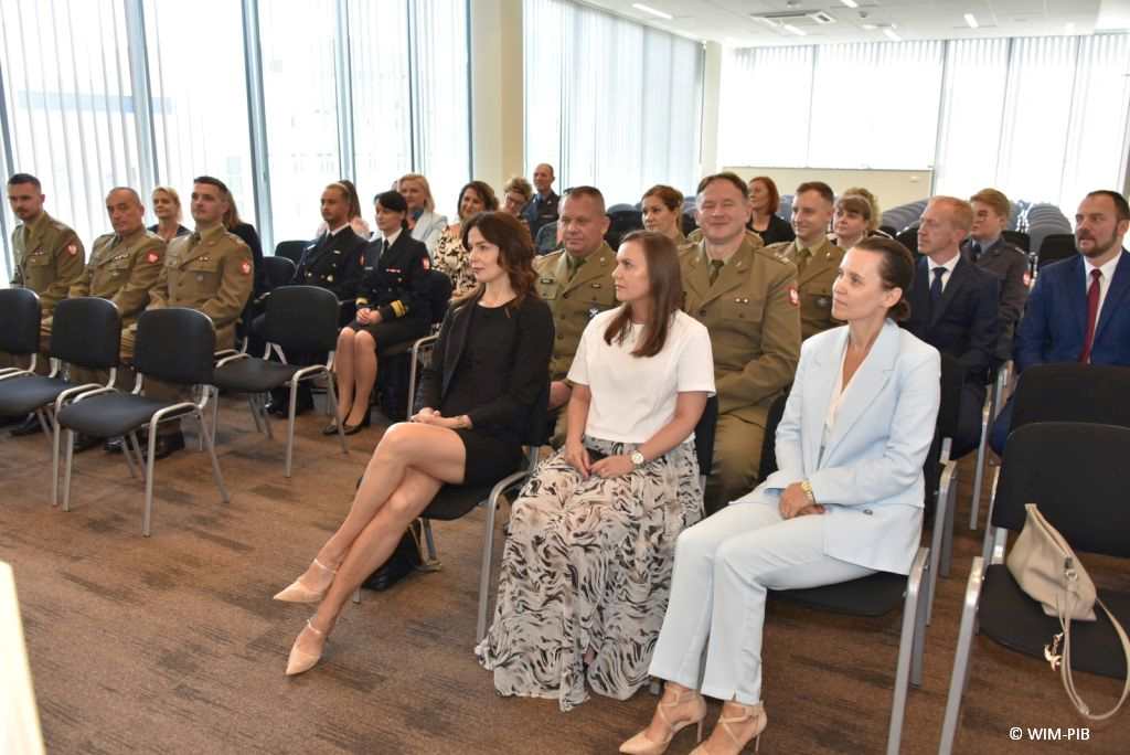 Uhonorowanie 30 absolwentów VIII edycji studiów podyplomowych w WIM-PIB, absolwenci siedzący na sali podczas uroczystości zakończenia studiów