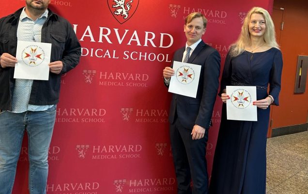 3 naukowców z WIM-PIB na tle napisu Harvard Medical School na czerwonym tle z dyplomami ukończenia kursu.