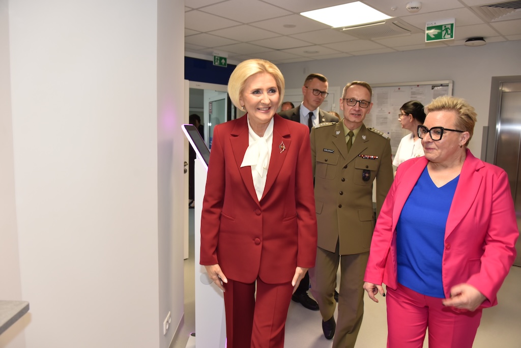 Na pierwszym planie Agata KORNHAUSER-DUDA, Lidia Wojda idą korytarzem oglądając nową Poradnię Chorób Piersi. Za nimi idzie dyrektor WIM Grzegorz Gielerak.
