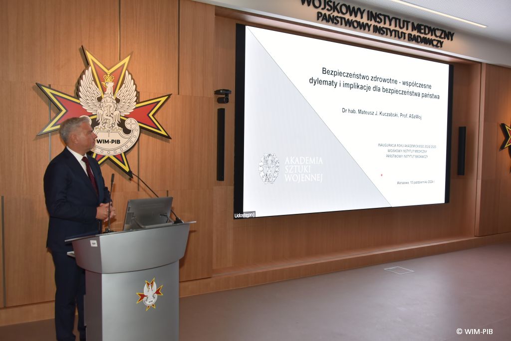 Relacja z Inauguracji Roku Akademickiego 2024/2025 w WIM-PIB. Prelegent prowadzi prezentację o bezpieczeństwie zdrowotnym.
