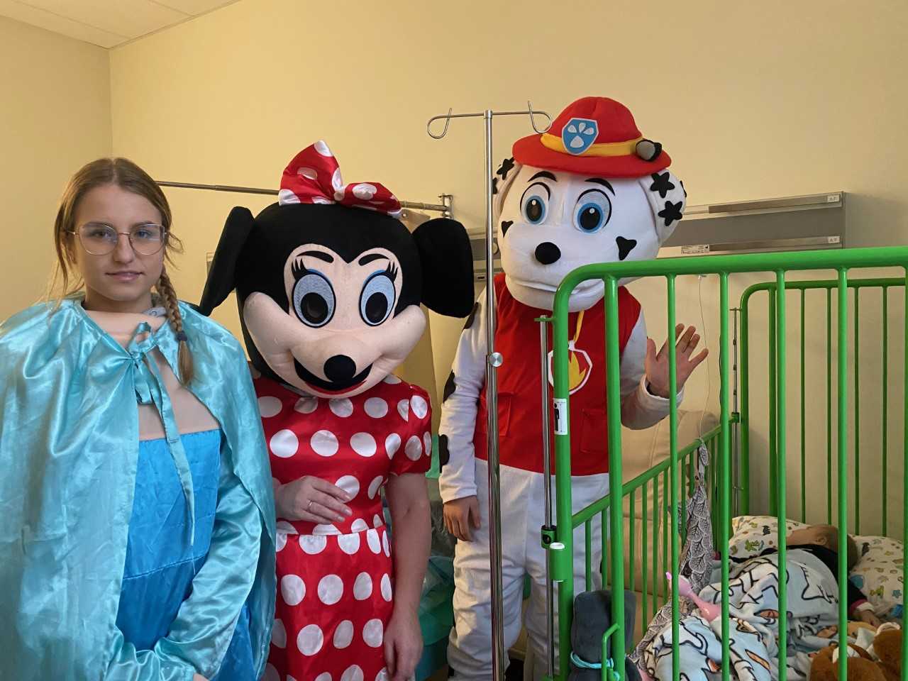 Mikołajki w Szpitalu w Legionowie. Goście z Ochotniczej Straży Pożarnej w Jadowie, przedstawiciele sołectwa Wólki Sulejowskiej, członków Koła Łowieckiego Cyranka oraz Stowarzyszenia Gospodyń Wiejskich w Myszadłach przebrani z apostacie z kreskówki przy łóżeczku z niemowlakiem.