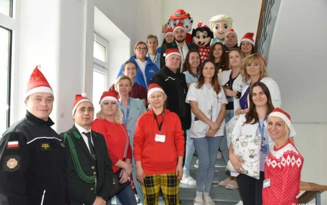 Zdjęcie kolorowe grupowe na schodach Kliniki Pediatrii WIM. Na schodach pracownicy WIM i goście z Ochotniczej Straży Pożarnej w Jadowie, przedstawiciele sołectwa Wólki Sulejowskiej, członkowie Koła Łowieckiego Cyranka oraz Stowarzyszenie Gospodyń Wiejskich w Myszadłach.