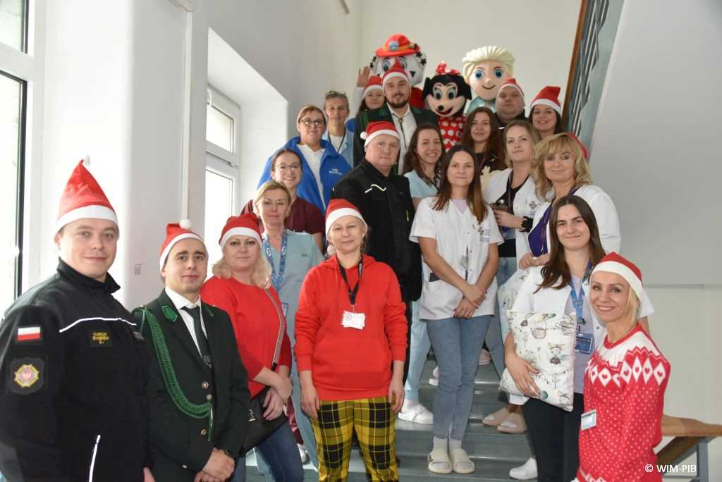 Zdjęcie kolorowe grupowe na schodach Kliniki Pediatrii WIM. Na schodach pracownicy WIM i goście z Ochotniczej Straży Pożarnej w Jadowie, przedstawiciele sołectwa Wólki Sulejowskiej, członkowie Koła Łowieckiego Cyranka oraz Stowarzyszenie Gospodyń Wiejskich w Myszadłach.