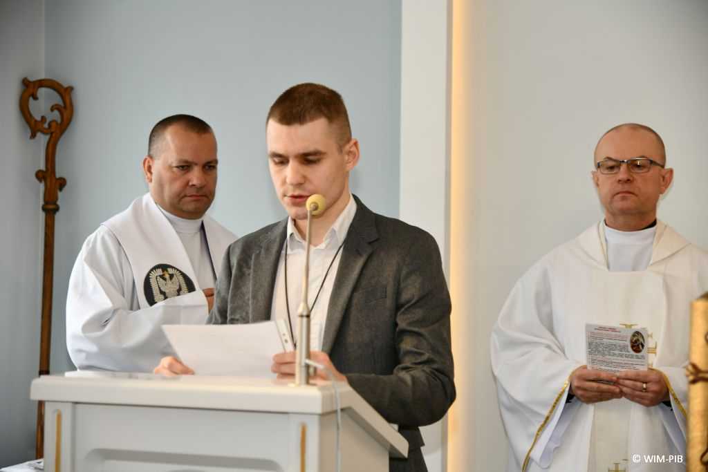 Msza święta w Wojskowym instytucie Medycznym. Pracownik WIM przy mównicy podczas mszy czyta z karki w dłoniach.