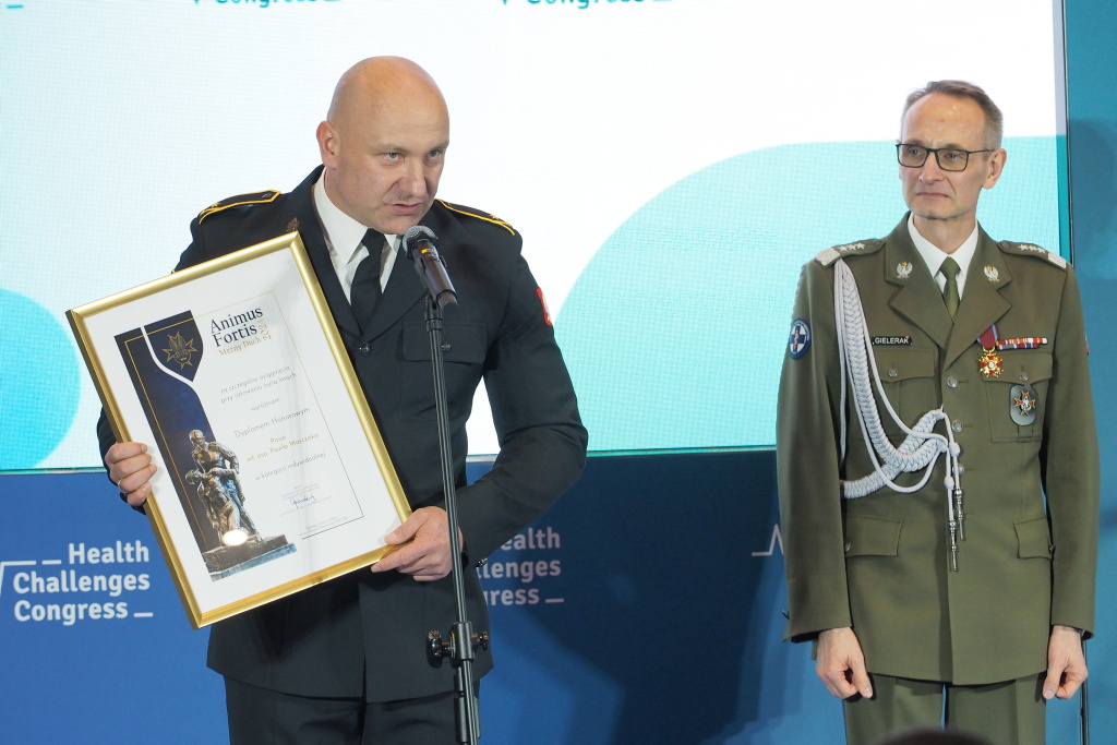 Paweł Marczak odbiera wyróżnienie Animus Fortis (Mężny Duch). W rękach trzyma wyróżnienie oprawione w złote ramy pochyla się nad mikrofonem aby wygłosić mowę