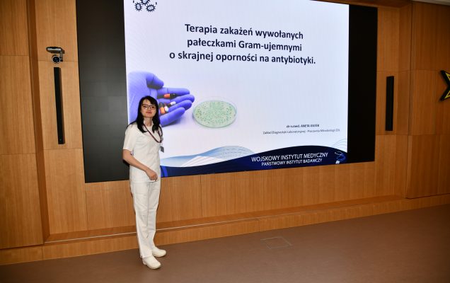 Anna Guzek podczas wykładu. Za nią tablica z tytułem wykładu.