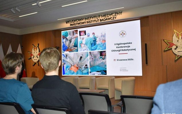 Słuchacze konferencji na sali, przed nimi na ekranie wyświetlony slajd z konferencji.