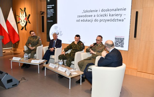 Uczestnicy siedzący w fotelach podczas panelu dyskusyjnego, za ich plecami wyświetlony fragment prezentacji, Grzegorz Gielerak wypowiada się.