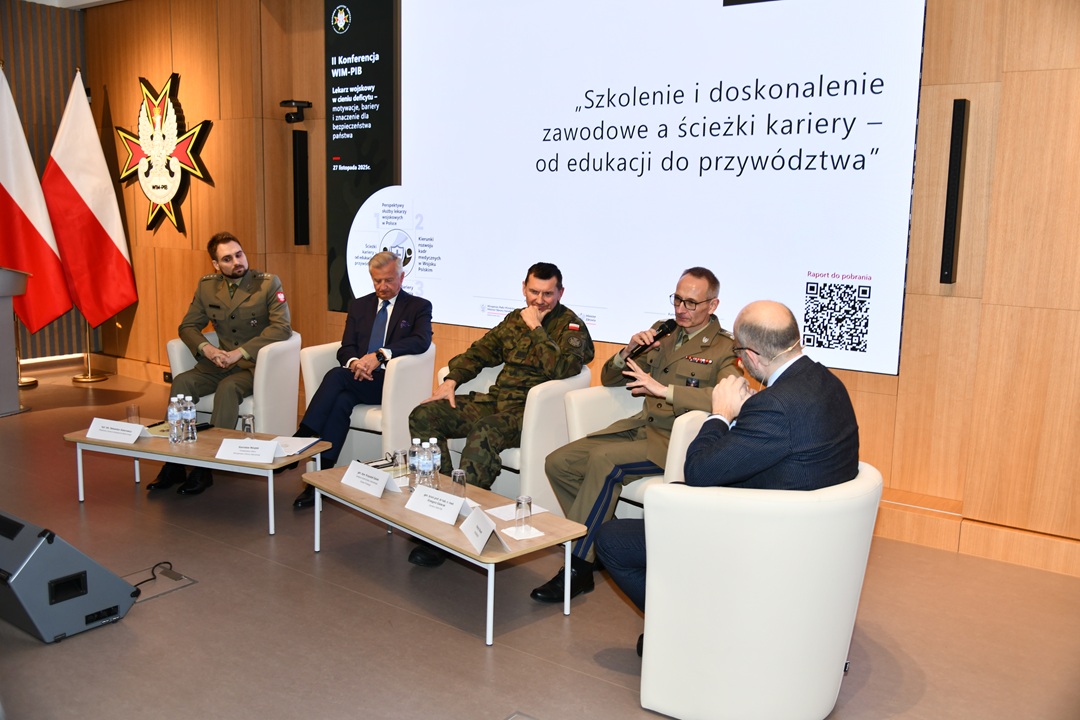 Uczestnicy siedzący w fotelach podczas panelu dyskusyjnego, za ich plecami wyświetlony fragment prezentacji, Grzegorz Gielerak wypowiada się.