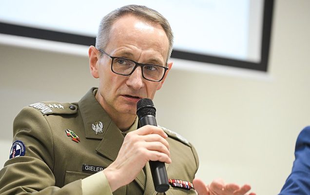 Grzegorz Gielerak w mundurze z mikrofonem w dłoni.