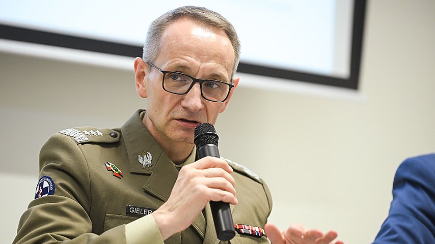 Grzegorz Gielerak w mundurze z mikrofonem w dłoni.