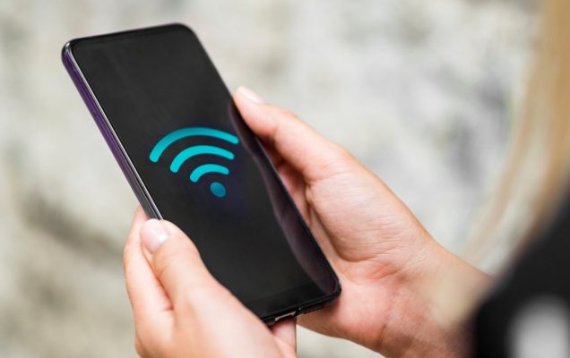 Telefon komórkowy w dłoniach z wyświetlonym na ekranie symbolem fi-fi.