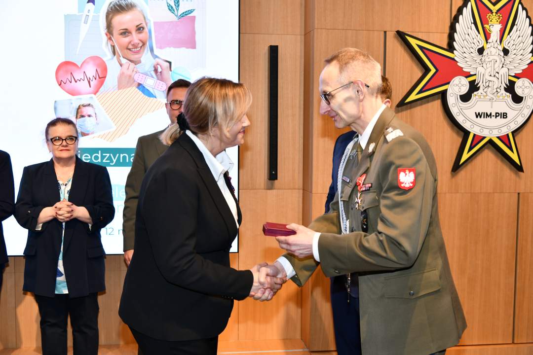Dyrektor WIM wręcza pielęgniarce odznaczenie.