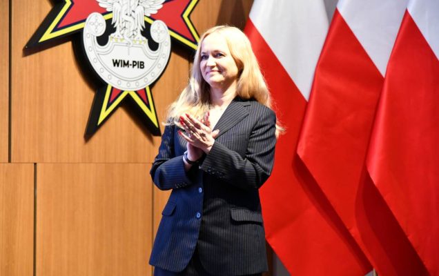 Ministra Zdrowia bije brawo na tle flagi Polski.
