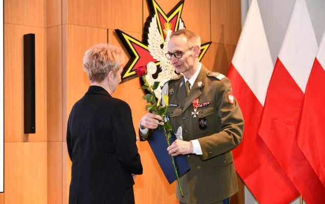 Dyrektor WIM wręcza pielęgniarce czerwoną różę i odznaczenie.