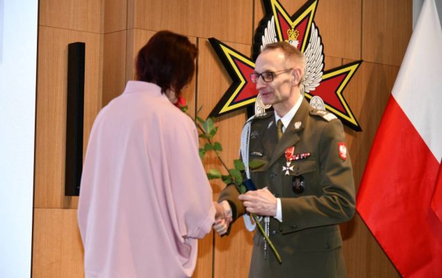 Dyrektor WIM wręcza czerwoną różę pielęgniarce.