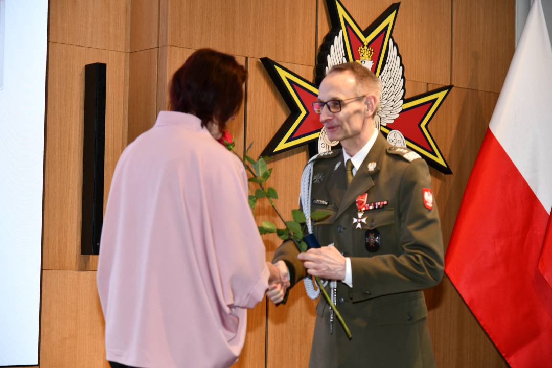Dyrektor WIM wręcza czerwoną różę pielęgniarce.