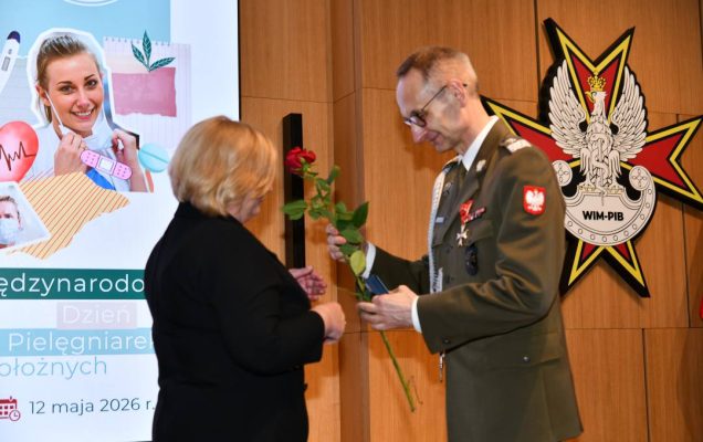 Dyrektor WIM wręcza czerwoną różę pielęgniarce.