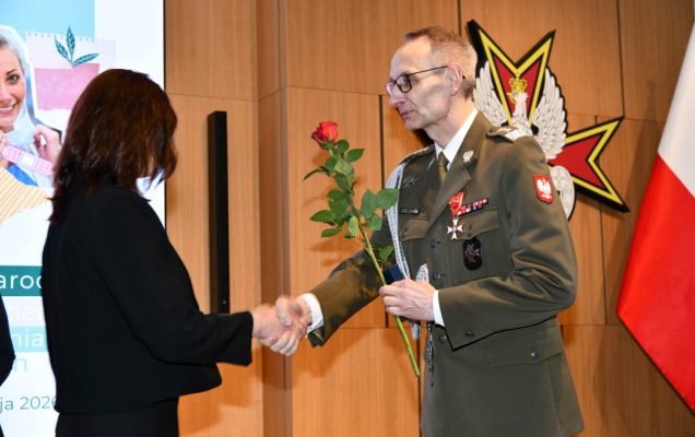 Dyrektor WIM wręcza czerwoną różę pielęgniarce.