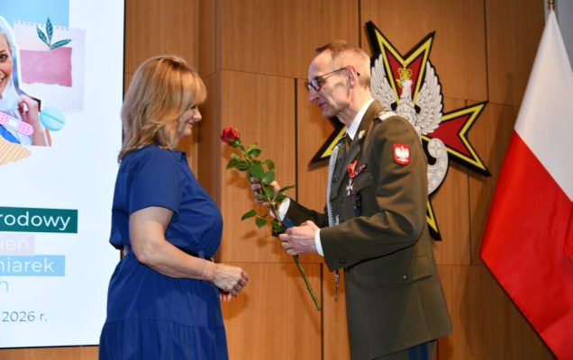 Dyrektor WIM wręcza czerwoną różę pielęgniarce.