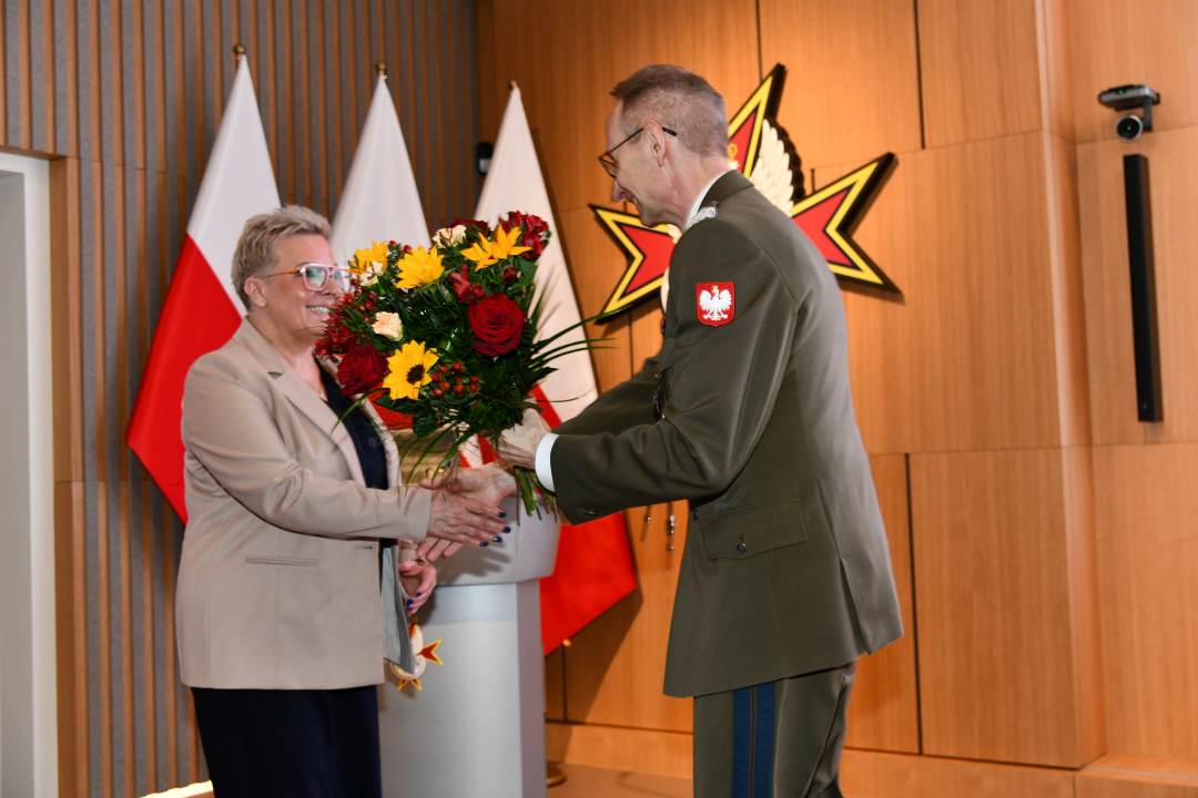 Dyrektor Wim wręcza Lidii Wojdzie bukiet kwiatów.