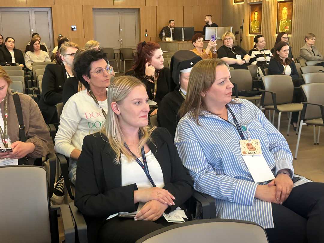 Siedzący słuchacze i prelegenci konferencji.