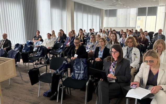 Siedzący słuchacze i prelegenci podczas konferencji na sali wykładowej WIM.