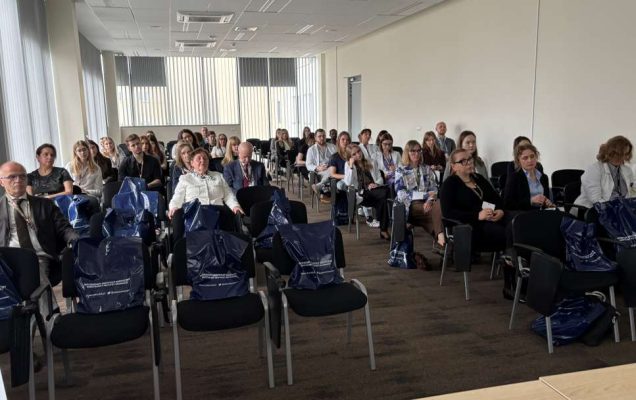 Siedzący słuchacze i prelegenci podczas konferencji na sali wykładowej WIM.