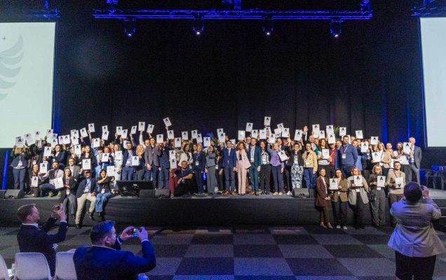 Zdjęcie grupowe laureatów Angel Initative na sali konferencyjnej.
