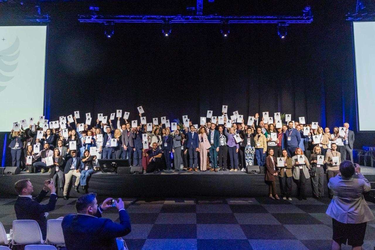 Zdjęcie grupowe laureatów Angel Initative na sali konferencyjnej.