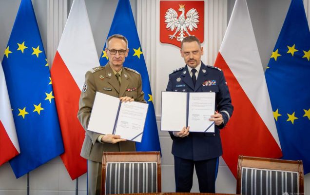 Grzegorz Gielerak i Roman Smogorzewski prezentują podpisane listy intencyjne. Za ich plecami godło RP oraz flagi UE i RP.