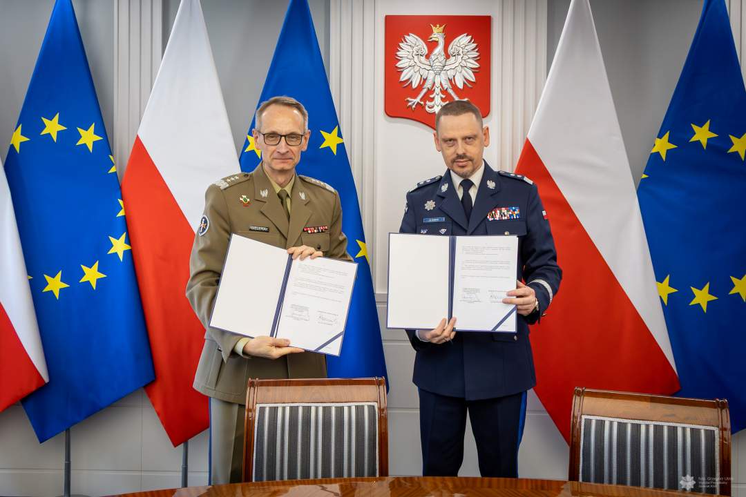 Grzegorz Gielerak i Roman Smogorzewski prezentują podpisane listy intencyjne. Za ich plecami godło RP oraz flagi UE i RP.