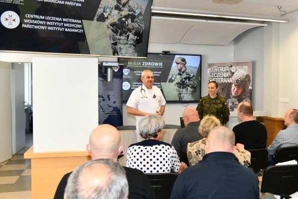 Prelegenci i siedzący na przeciw nich słuchacze w sali wykładowej.