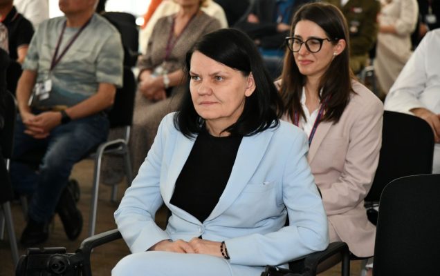 Katarzyna Kacperczyk siedzi na sali podczas uroczystości. Za nią w następnym rzędzie siedzi Justyna Chałubińska-Fendler.