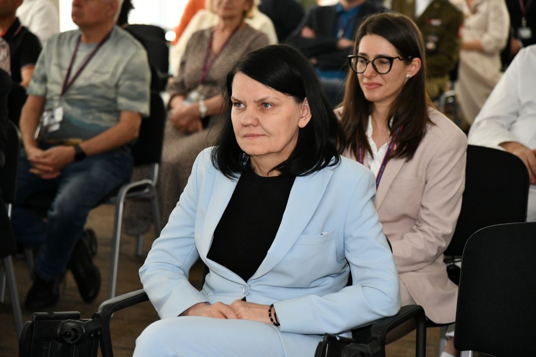 Katarzyna Kacperczyk siedzi na sali podczas uroczystości. Za nią w następnym rzędzie siedzi Justyna Chałubińska-Fendler.