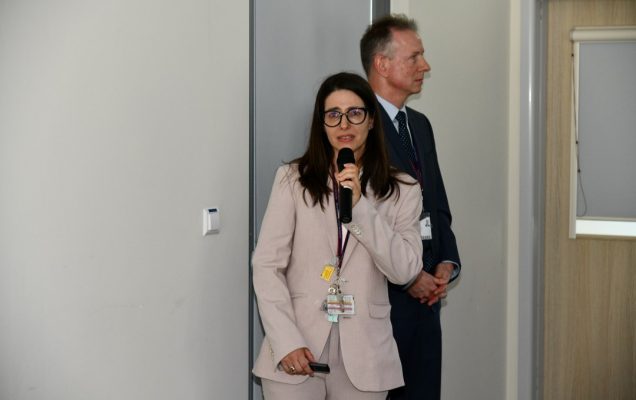 Justyna Chałubińska-Fendler z mikrofonem w ręku prowadzi prezentację.